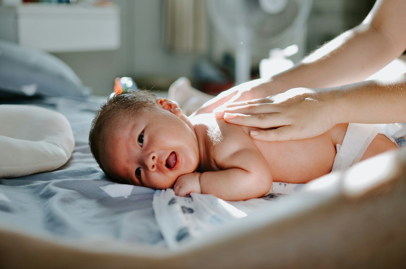 Photo by Khoa Pham baby laying on bed while woman massaging his back